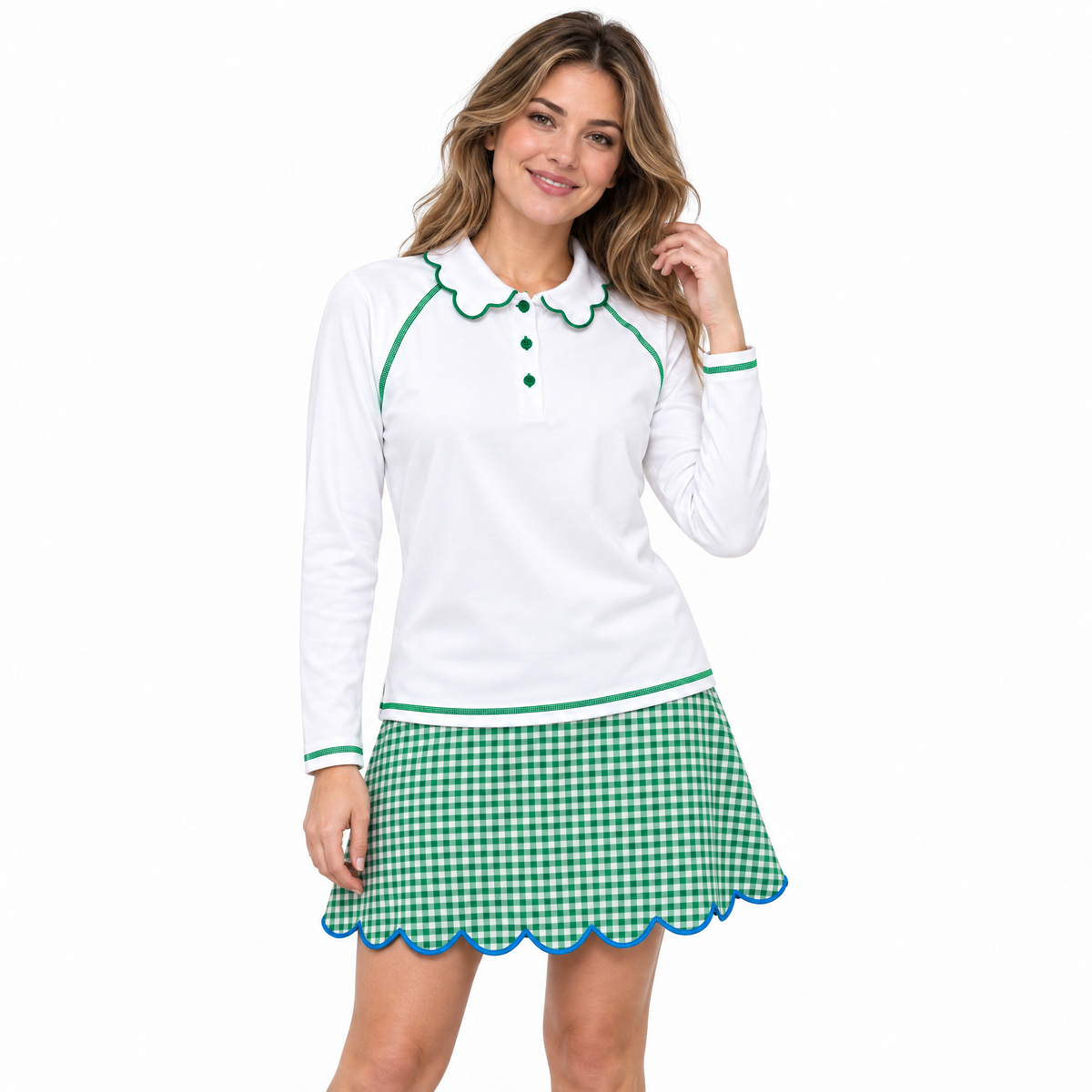 A woman modeling a white long-sleeve polo shirt with green trim and a green-and-white gingham mini skirt with a blue scalloped hem, against a plain white background.