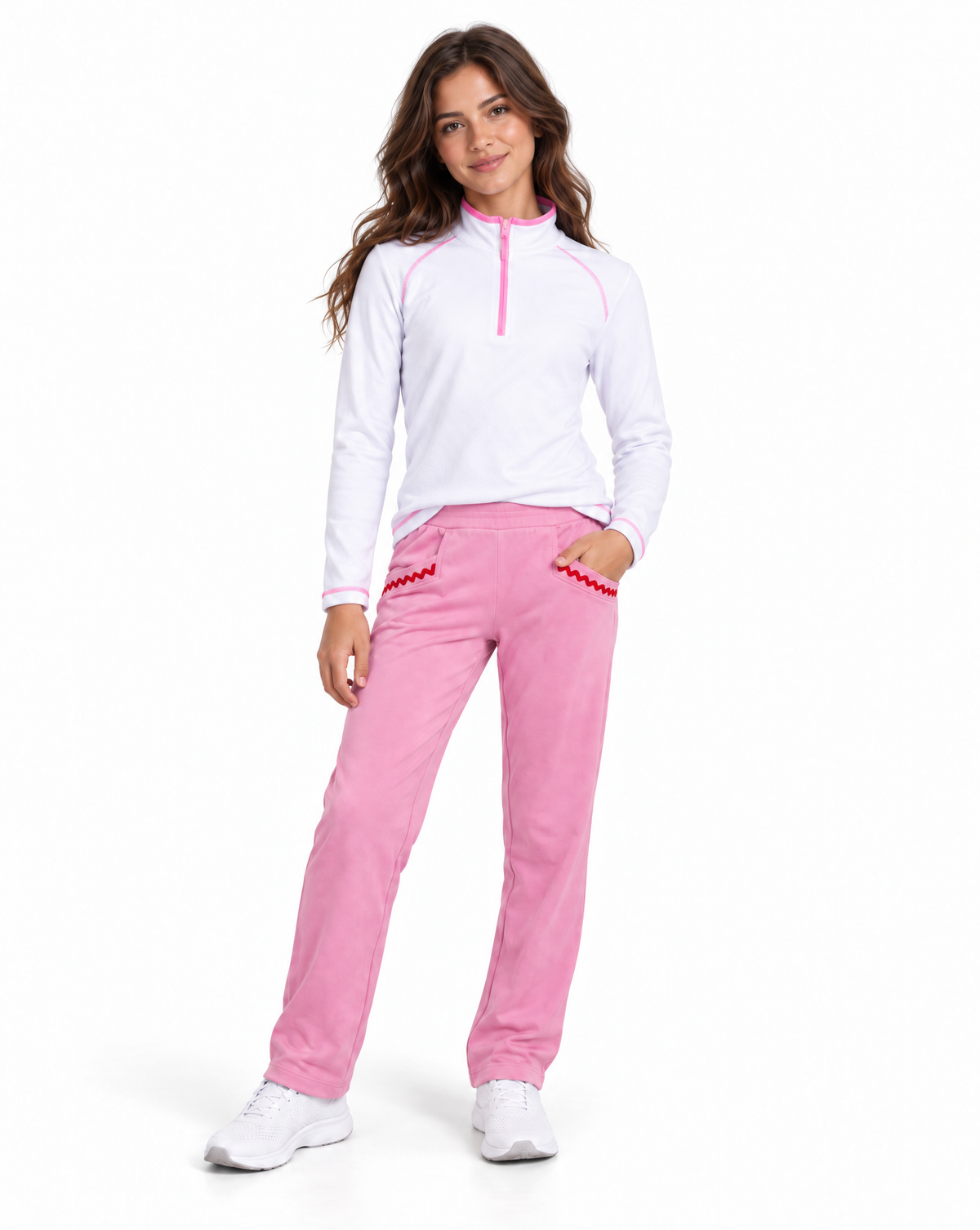 A woman modeling a white long-sleeve quarter-zip athletic top with pink trim and matching pink pants with red trim, standing against a plain white background.