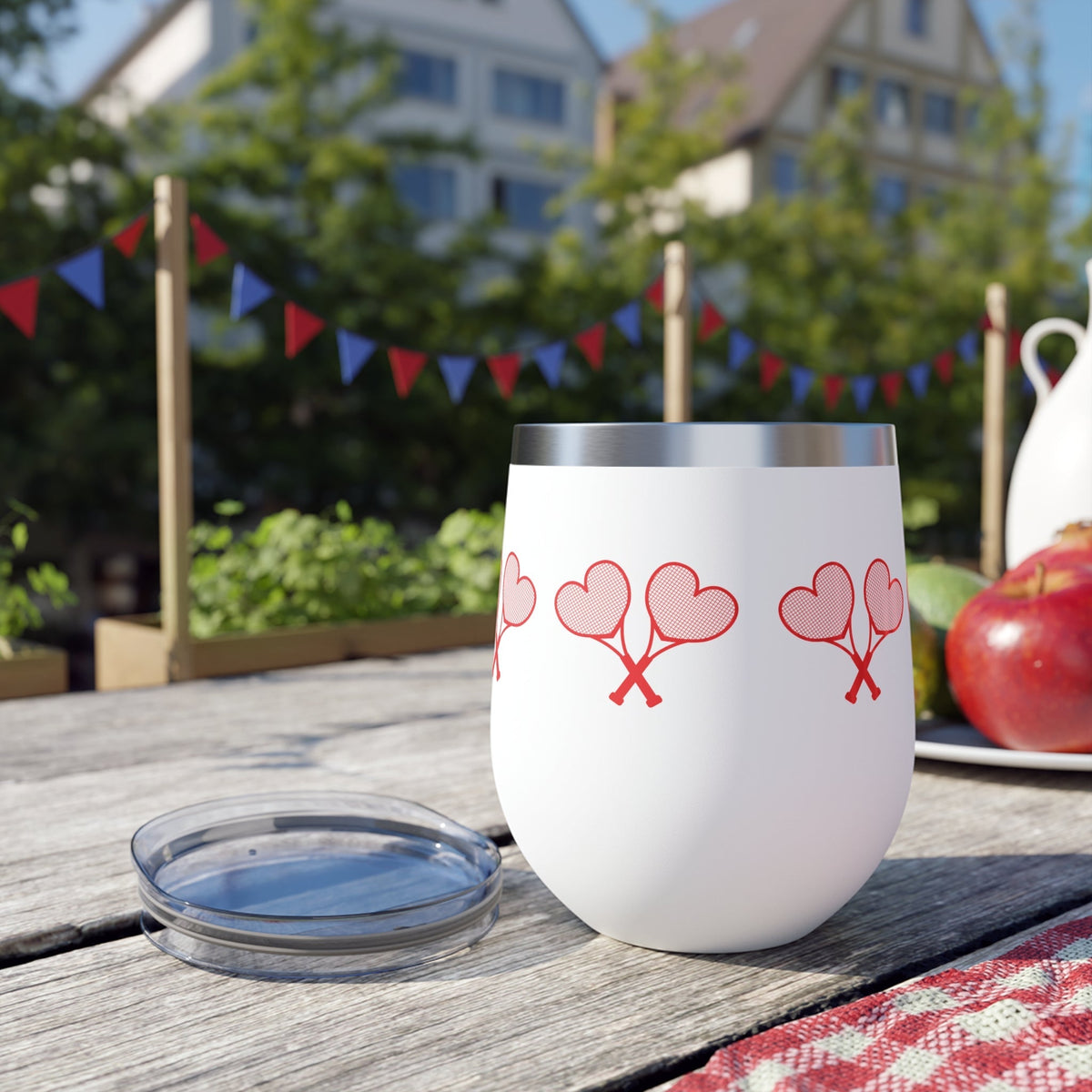 White tumbler with red heart designs on a picnic table