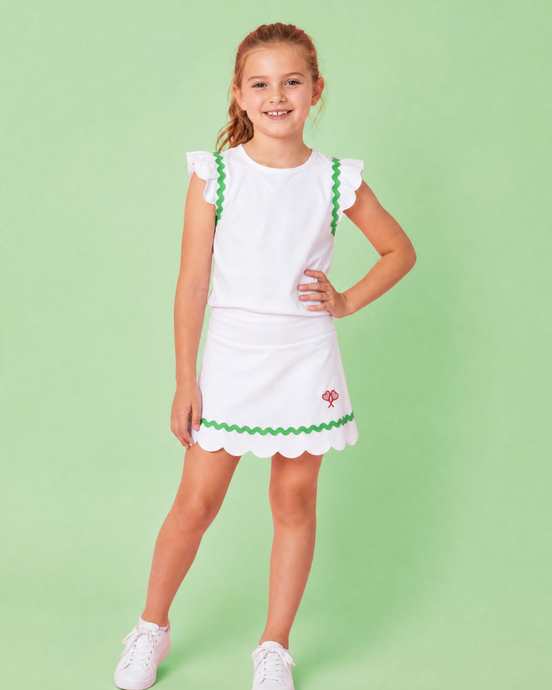 Young girl wearing a white dress with green trim against a light green background