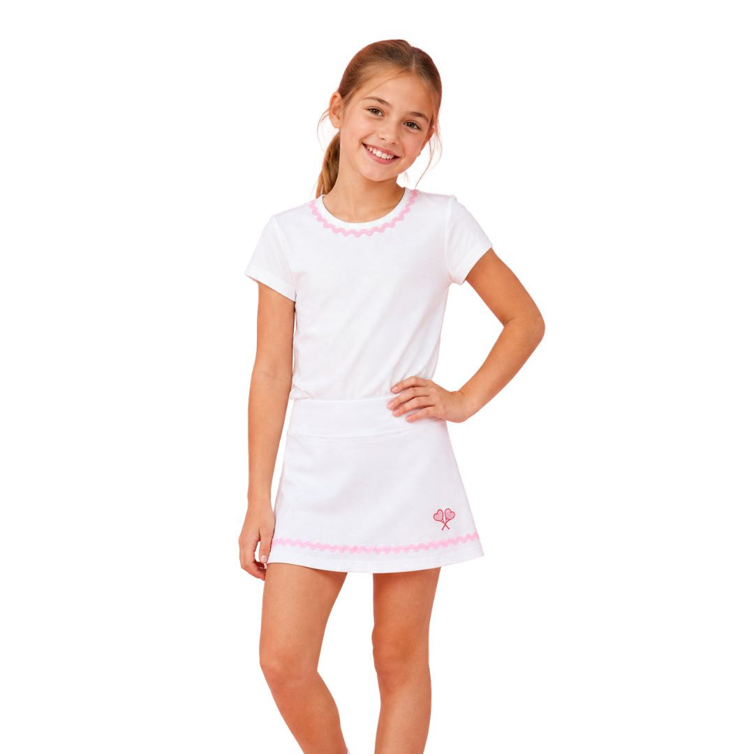 Young girl wearing a white dress with pink trim on a white background