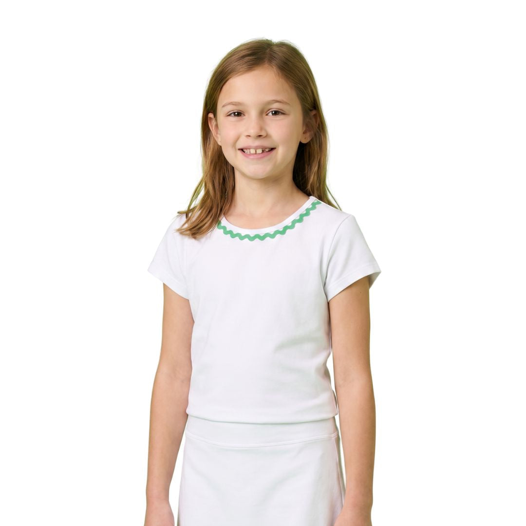 Young girl wearing a white outfit with green trim on a white background