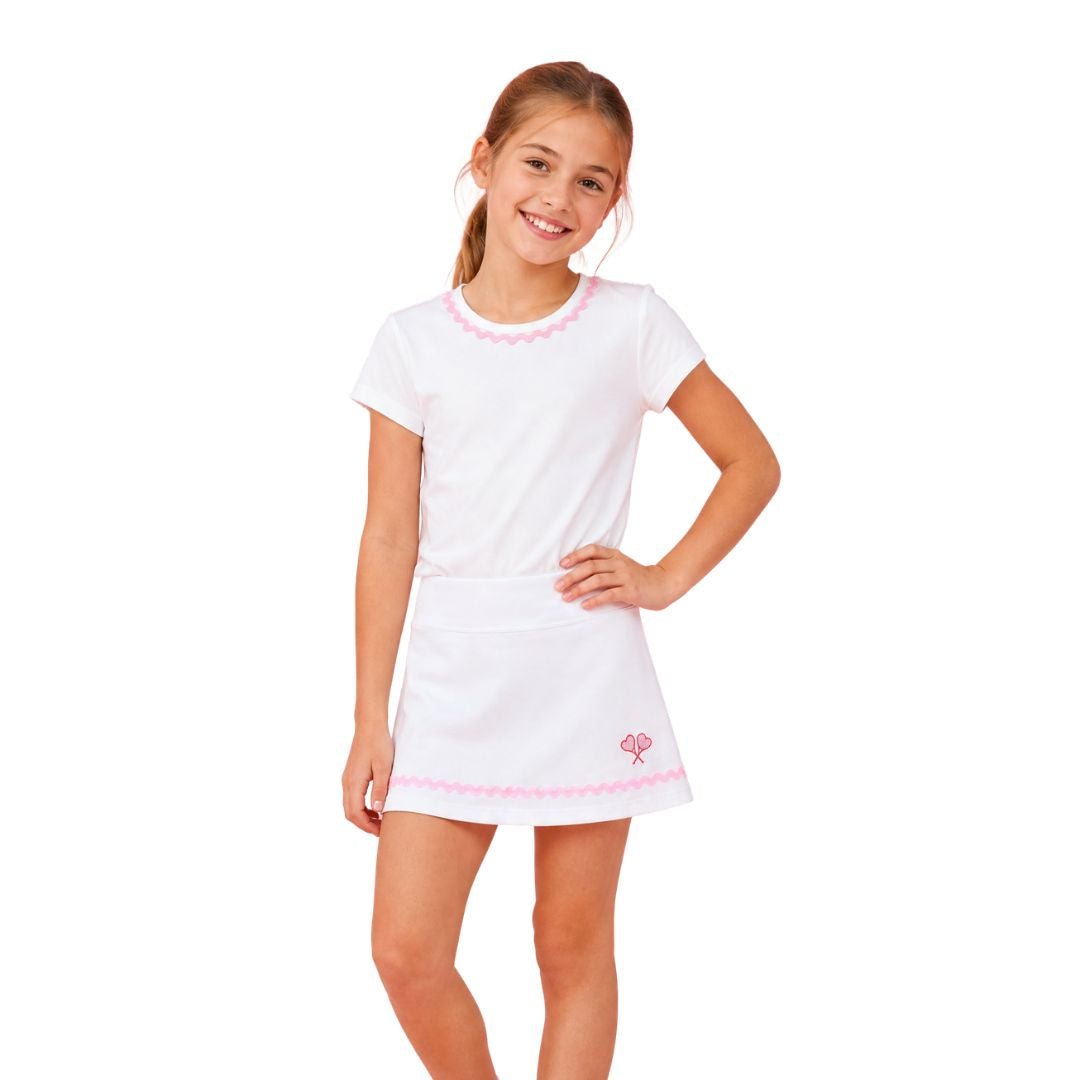 Young girl wearing a white dress with pink trim on a white background