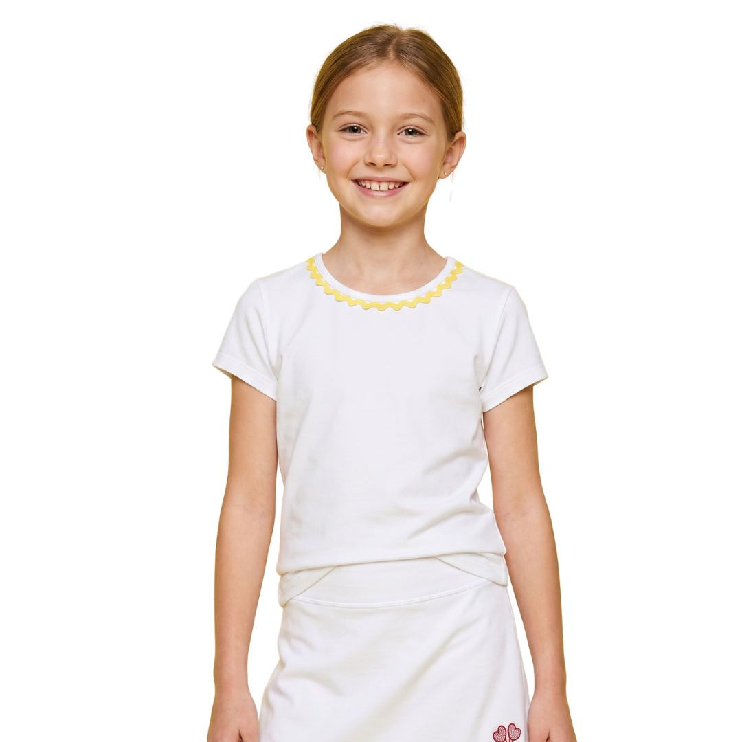 Young girl wearing a white top and skirt with yellow trim on a white background