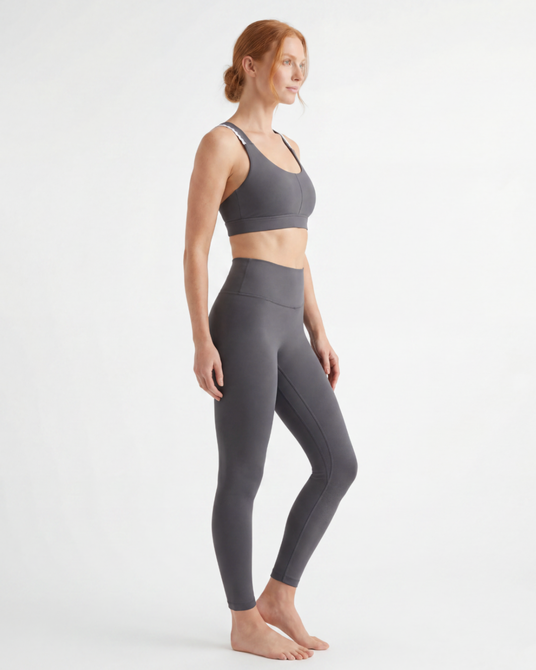 Woman wearing a gray sports bra and leggings on a white background