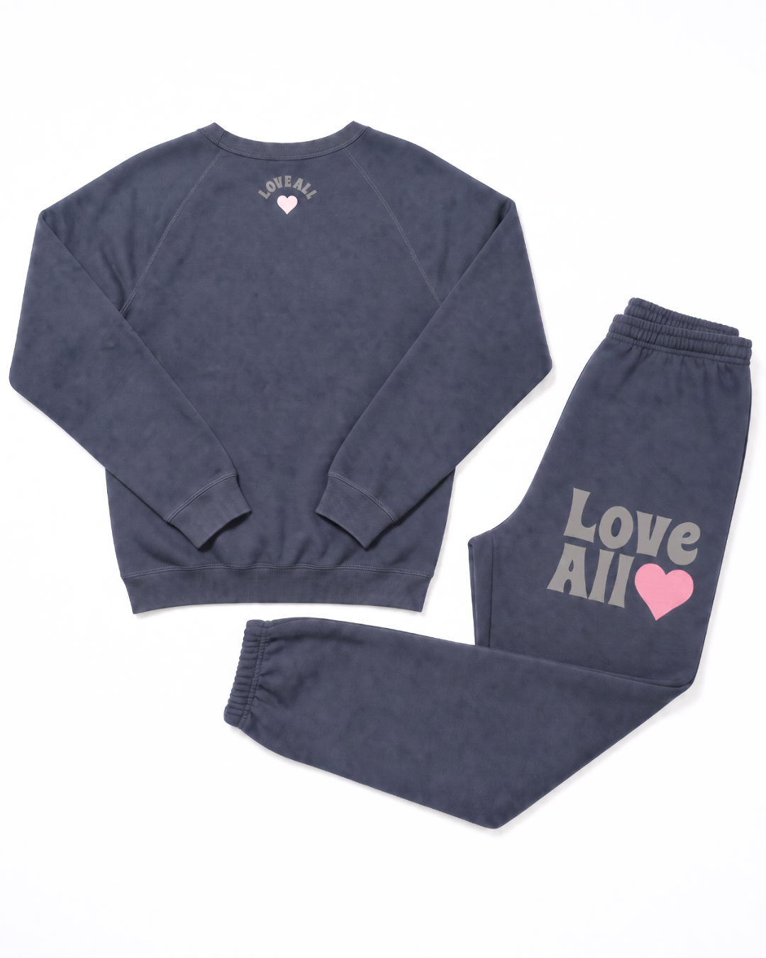 A two-piece lounge set consisting of a crewneck sweatshirt and matching joggers in a washed grey color. The sweatshirt features a small white heart and text on the back, while the joggers feature 'Love All' in white text and a pink heart on the left thigh
