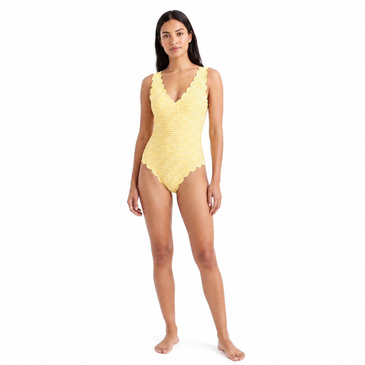 A woman modeling a yellow and white gingham-patterned one-piece swimsuit with scalloped edges, standing against a solid white background.