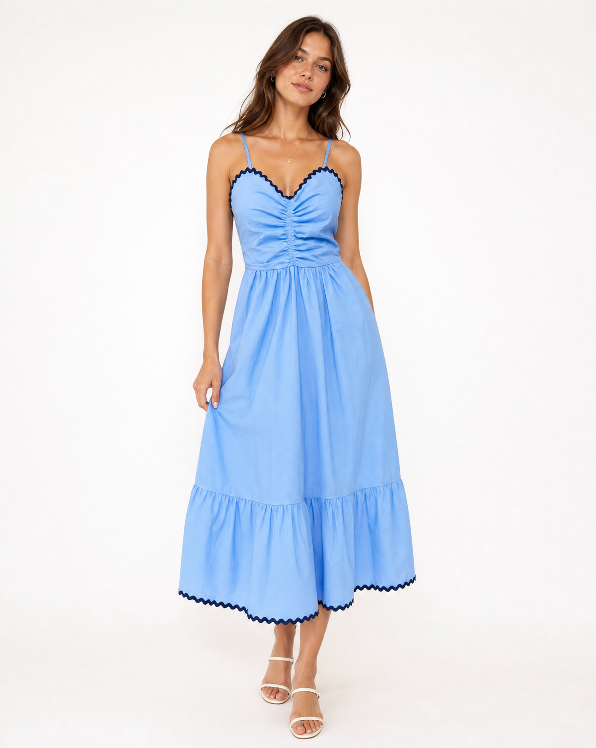 Woman in blue and navy thin strapped dress on white background