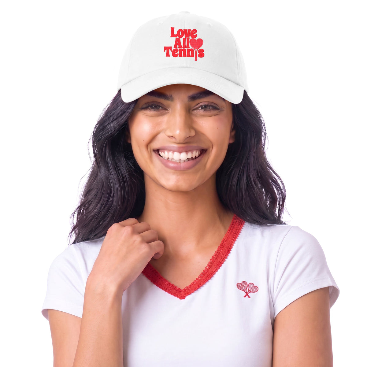 A smiling woman wearing a white baseball cap with red embroidered text reading 'Love All Tennis' and a small red tennis racket logo on the chest, paired with a white V-neck T-shirt with red trim.