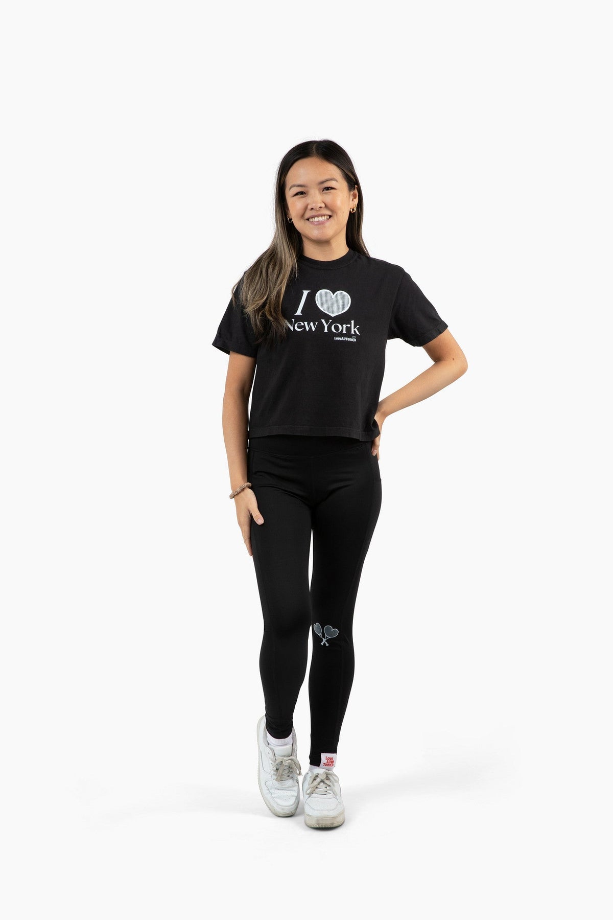 Person wearing a black t-shirt with 'I ❤️ New York' text and black leggings on a white background