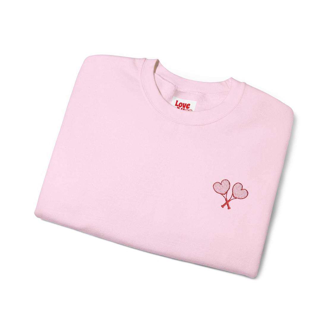 Folded pink sweatshirt with heart design and 'Love' text on a white background
