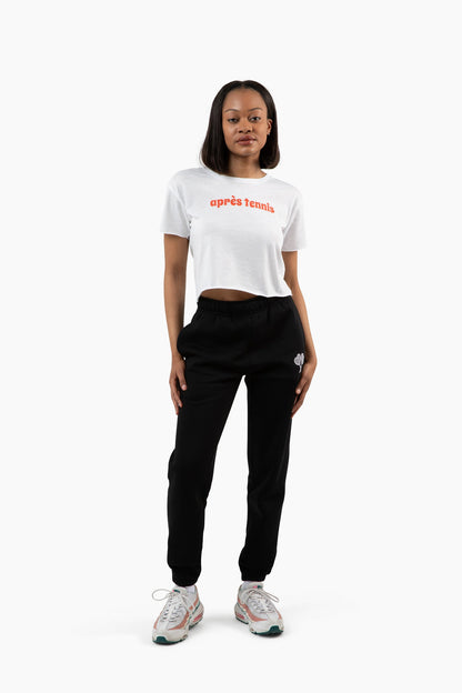 Person wearing a white cropped t-shirt with red text and black pants on a white background