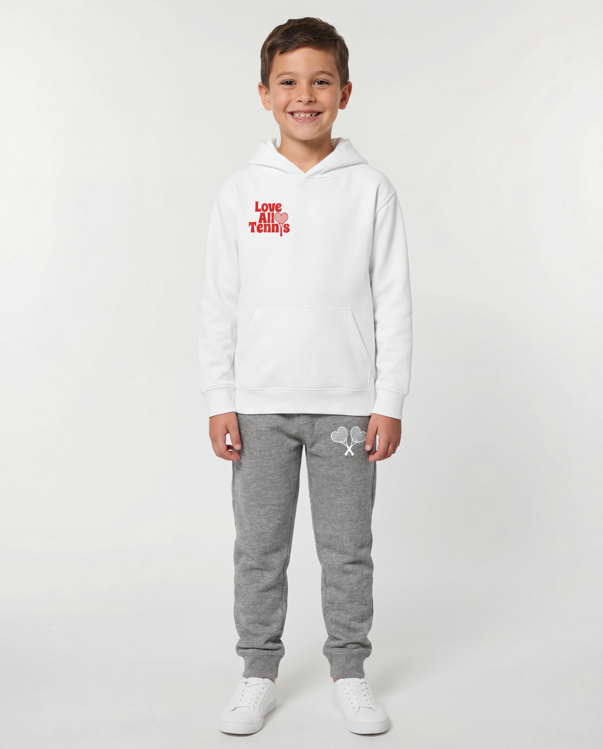 Boy wearing a white sweatshirt with red logo and white sweatpants with white logo on grey studio background