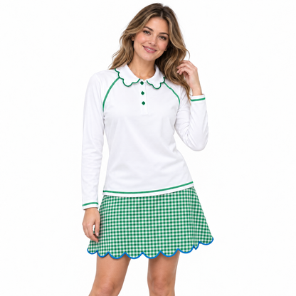 A woman modeling a white long-sleeve polo shirt with green trim and a green-and-white gingham mini skirt with a blue scalloped hem, against a plain white background.