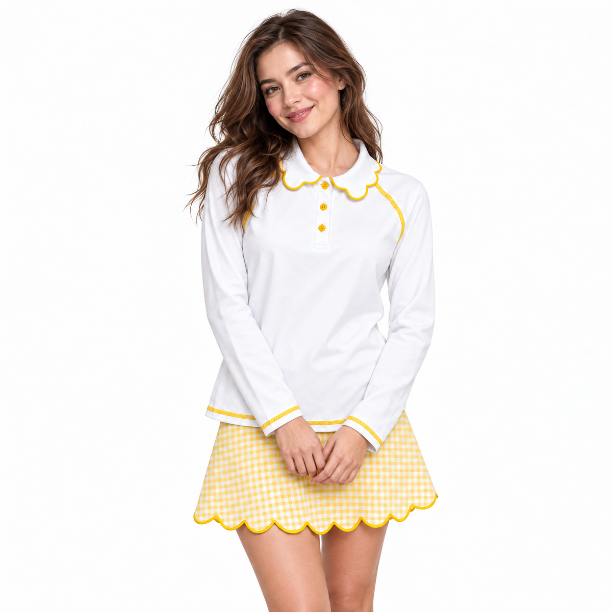 A woman modeling a white long-sleeve collared shirt with yellow trim and a matching yellow-and-white gingham mini skirt with a scalloped yellow trim, against a plain white background.