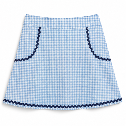 A light blue and white gingham skirt with dark navy blue zigzag trim along the waistband, pocket edges, and bottom hem, shown flat against a white background.