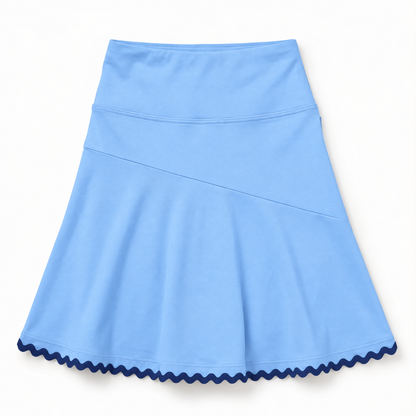 A light blue athletic skirt with a high-waisted design, diagonal seam detail, and a contrasting dark navy wavy scalloped hem, shown flat against a white background.