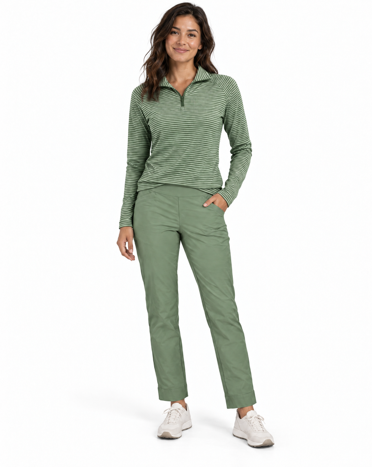A woman modeling a green and white striped long-sleeve quarter-zip pullover and matching green pants, paired with white sneakers, against a plain white background.