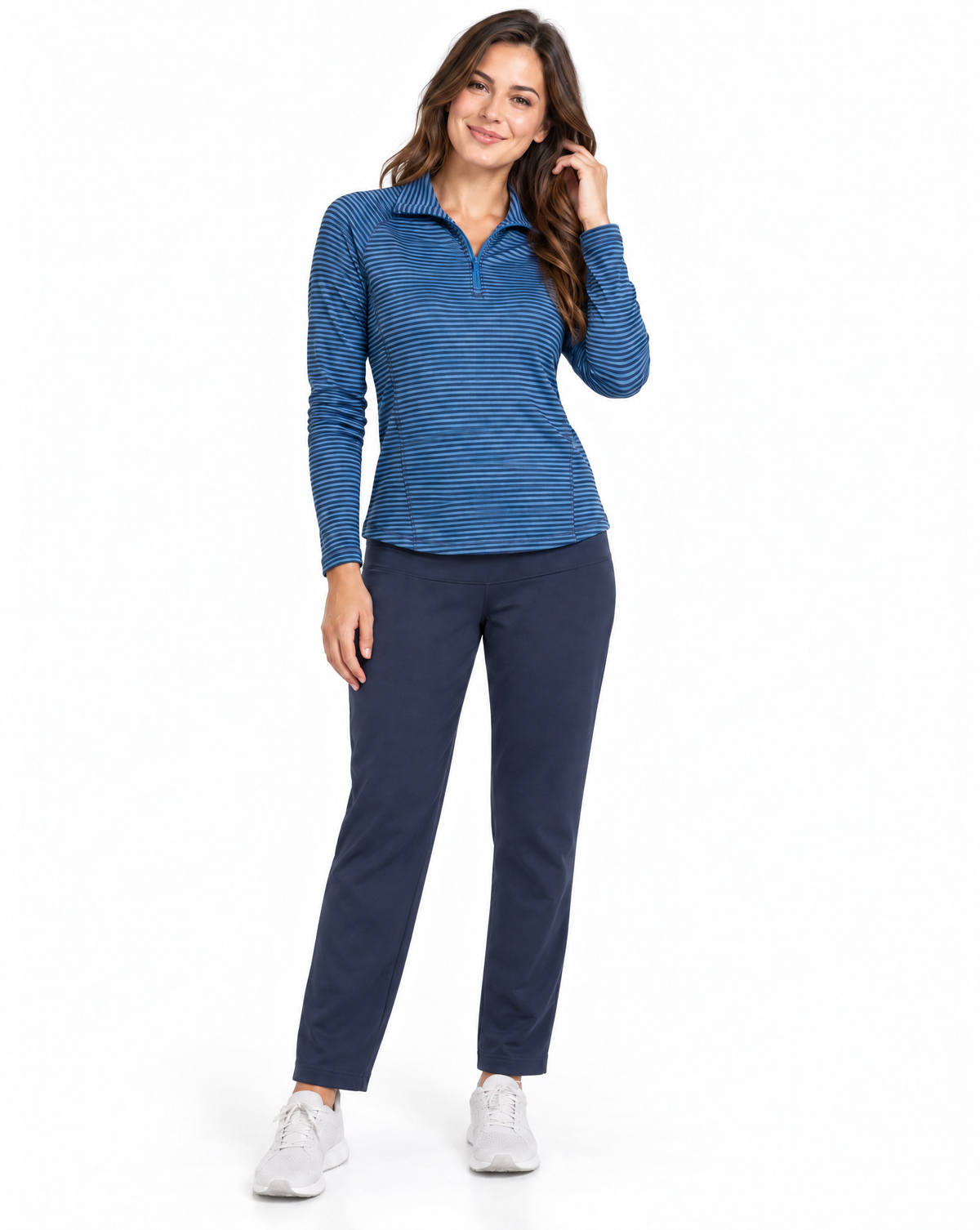 A woman modeling a blue and navy striped long-sleeve quarter-zip pullover top with navy pants and white sneakers, photographed against a solid white background.