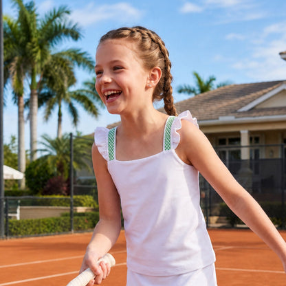 Young girl playing tennis on a clay court with palm trees in the background