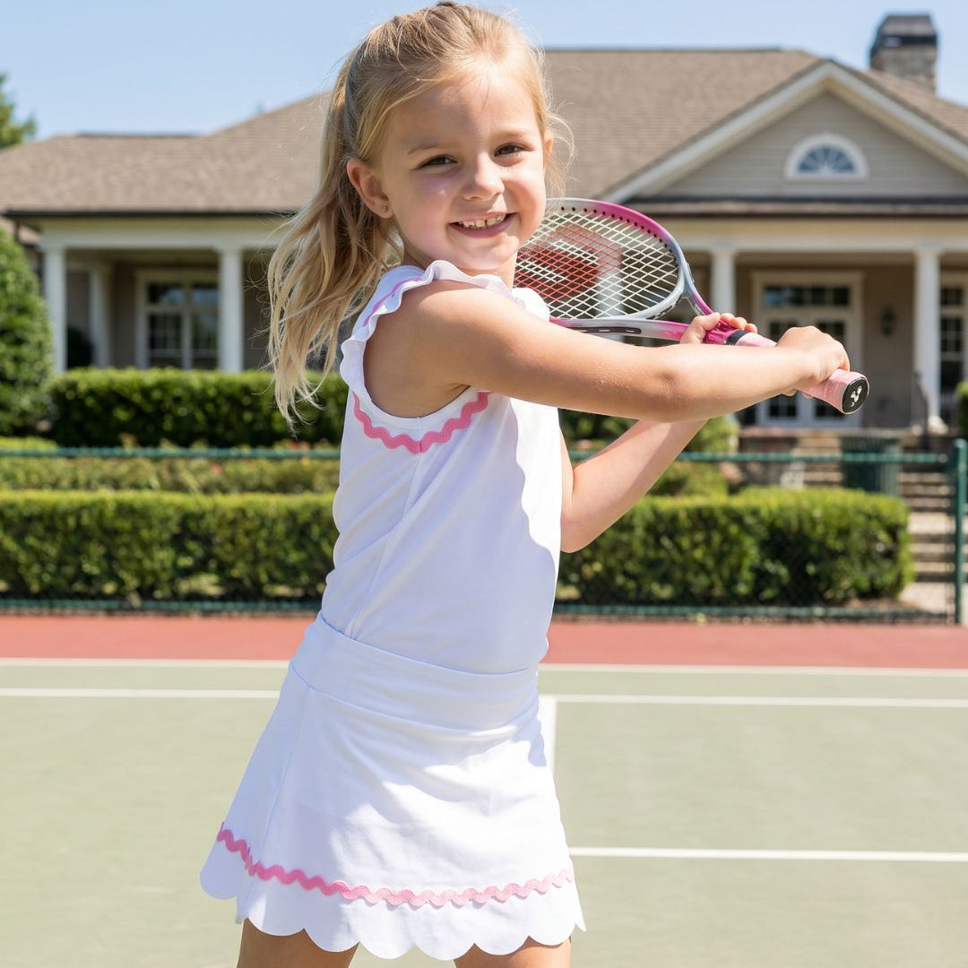 Young girl playing tennis on a court with a house in the background