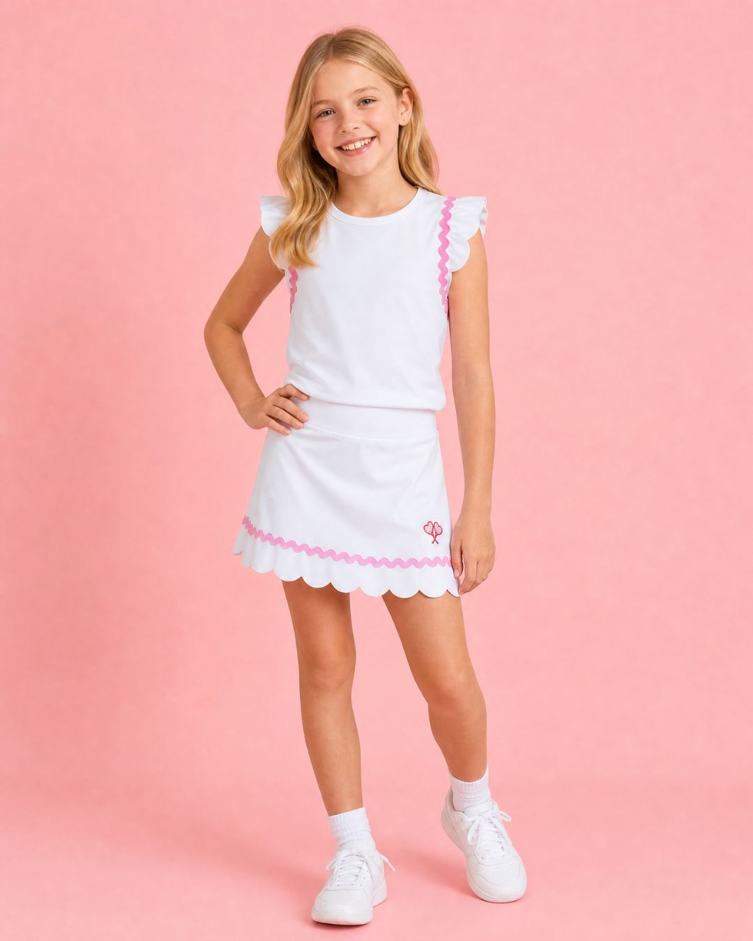 Young girl wearing a white dress with pink trim against a pink background
