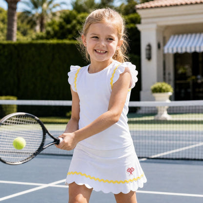 Young girl playing tennis on a court with a house and palm trees in the background