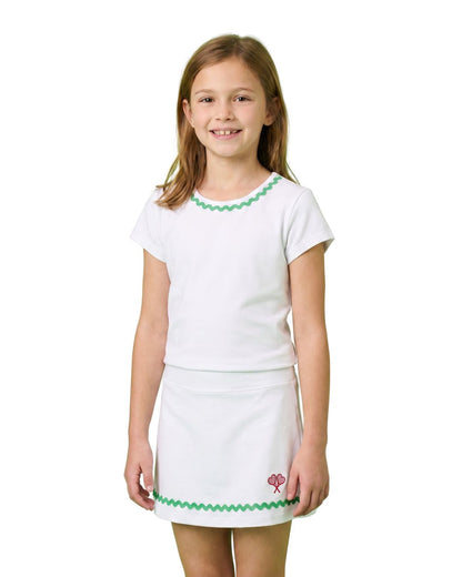 Young girl wearing a white outfit with green trim on a white background
