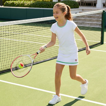 Young girl playing tennis on a court with a racket and ball.