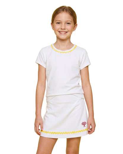 Young girl wearing a white dress with yellow trim on a white background