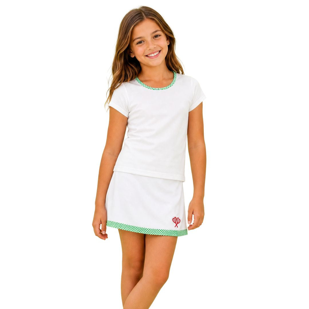 Young girl wearing a white outfit with a skirt and t-shirt on a white background