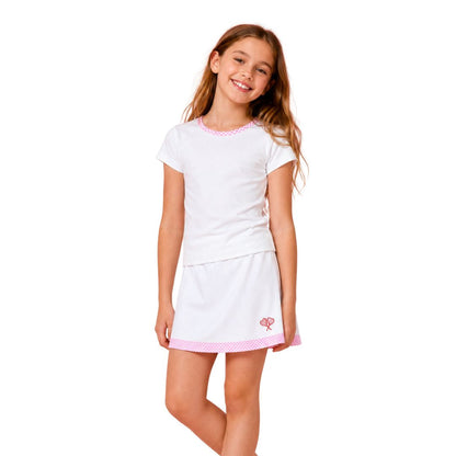 Young girl wearing a white tennis outfit with pink trim on a white background