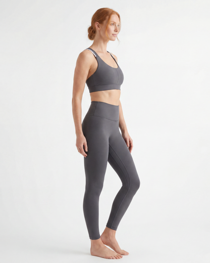Woman wearing a gray sports bra and leggings on a white background