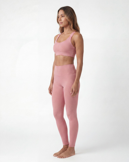 Woman wearing a pink sports bra and leggings set on a white background