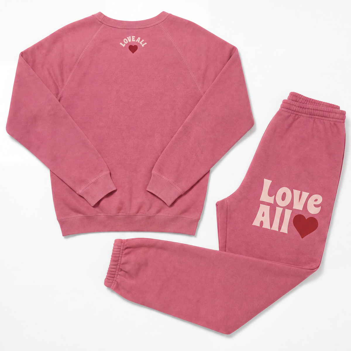 A two-piece matching loungewear set consisting of a long-sleeve sweatshirt and sweatpants in a dusty rose pink color. The sweatshirt features the text 'LOVE ALL' in a light pink arched font above a dark red heart on the upper back.