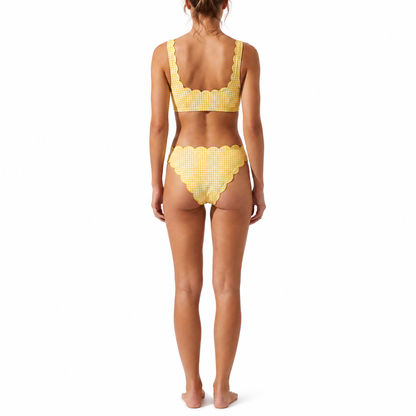 A woman modeling the back of a two-piece bikini swimsuit with a yellow and white gingham check pattern, standing against a solid white background.