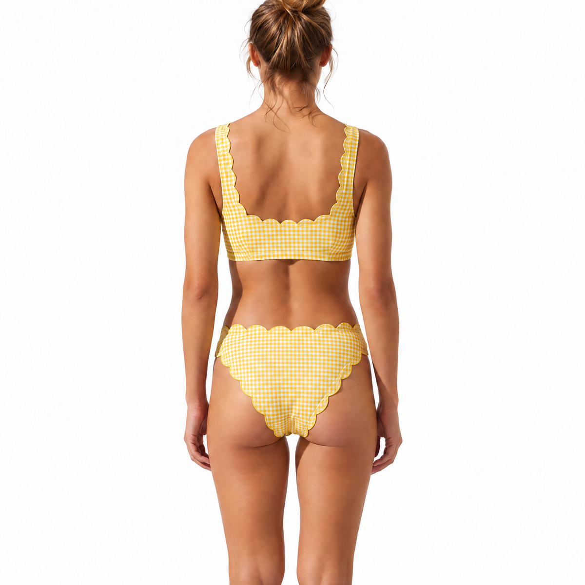 A woman viewed from the back wearing a yellow and white gingham bikini with scalloped edges, set against a plain white background.