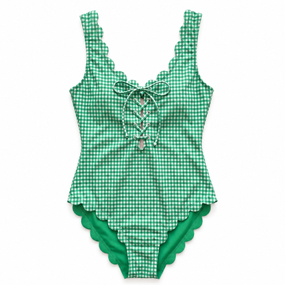 A green and white gingham one-piece swimsuit with scalloped edges, featuring a lace-up front detail with a silver heart-shaped charm.