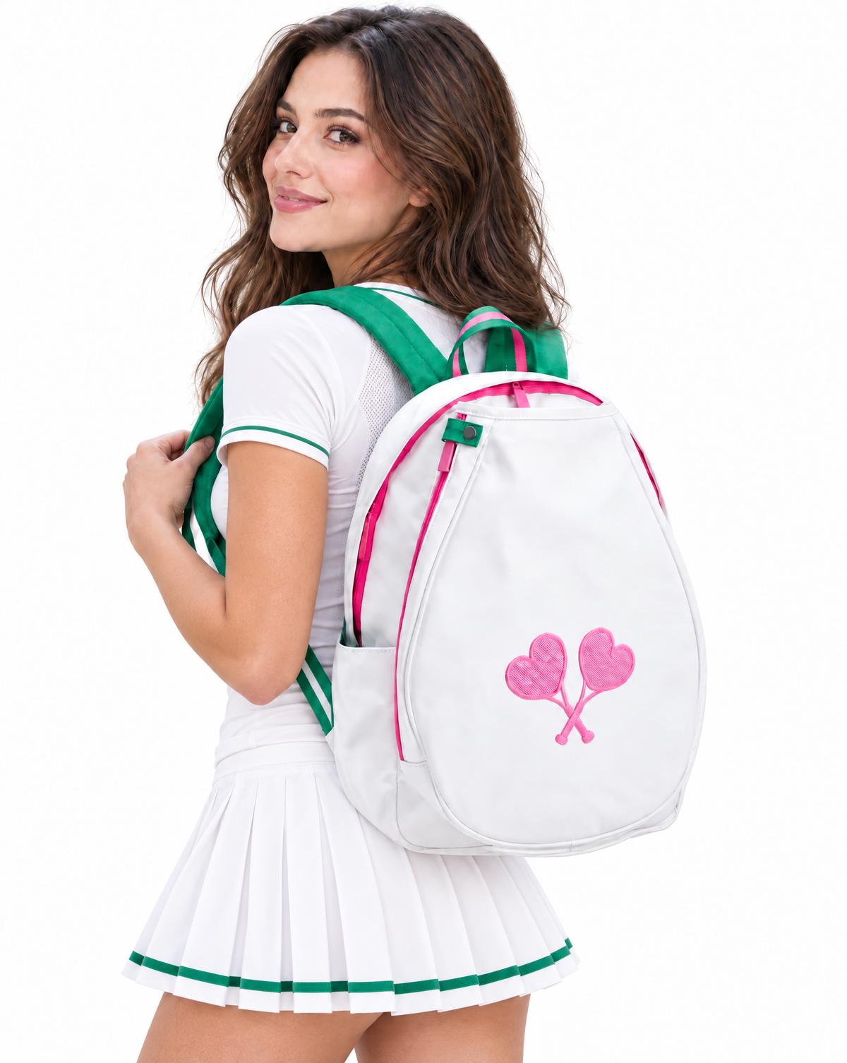 A woman wearing a white tennis dress with green and white trim, carrying a white backpack with green and pink straps and a pink heart design on the back, against a plain white background.