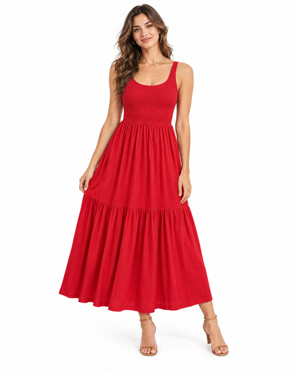 A woman modeling a sleeveless red maxi dress with a scoop neckline and a tiered skirt, standing against a plain white studio background.