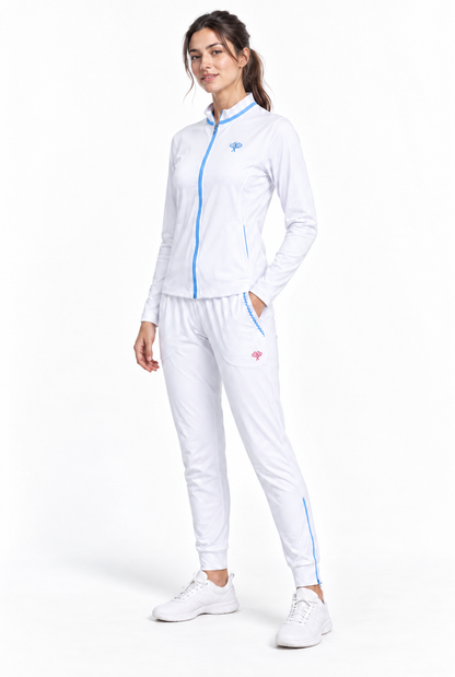 A woman modeling a white athletic tracksuit with light blue zipper accents and small pink logo details, paired with white sneakers, against a plain white studio background.