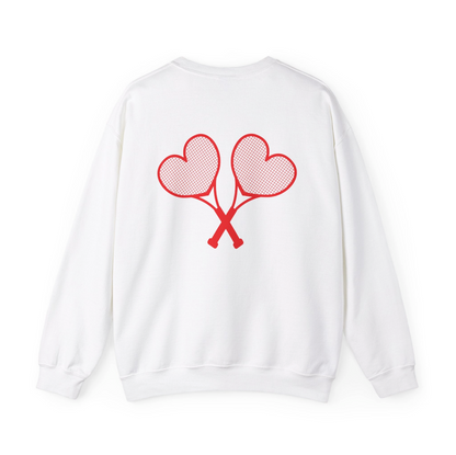 A white sweatshirt with red heart tennis rackets crossed on the back set against a white background