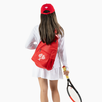 Person wearing a red backpack and holding a tennis racket on a white background