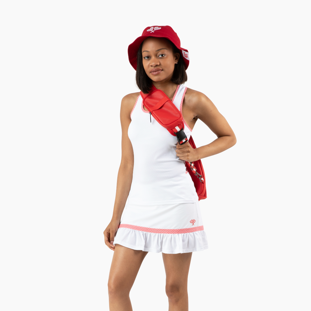 Person wearing a white tennis dress with red accents, holding a red tennis racket, on a white background