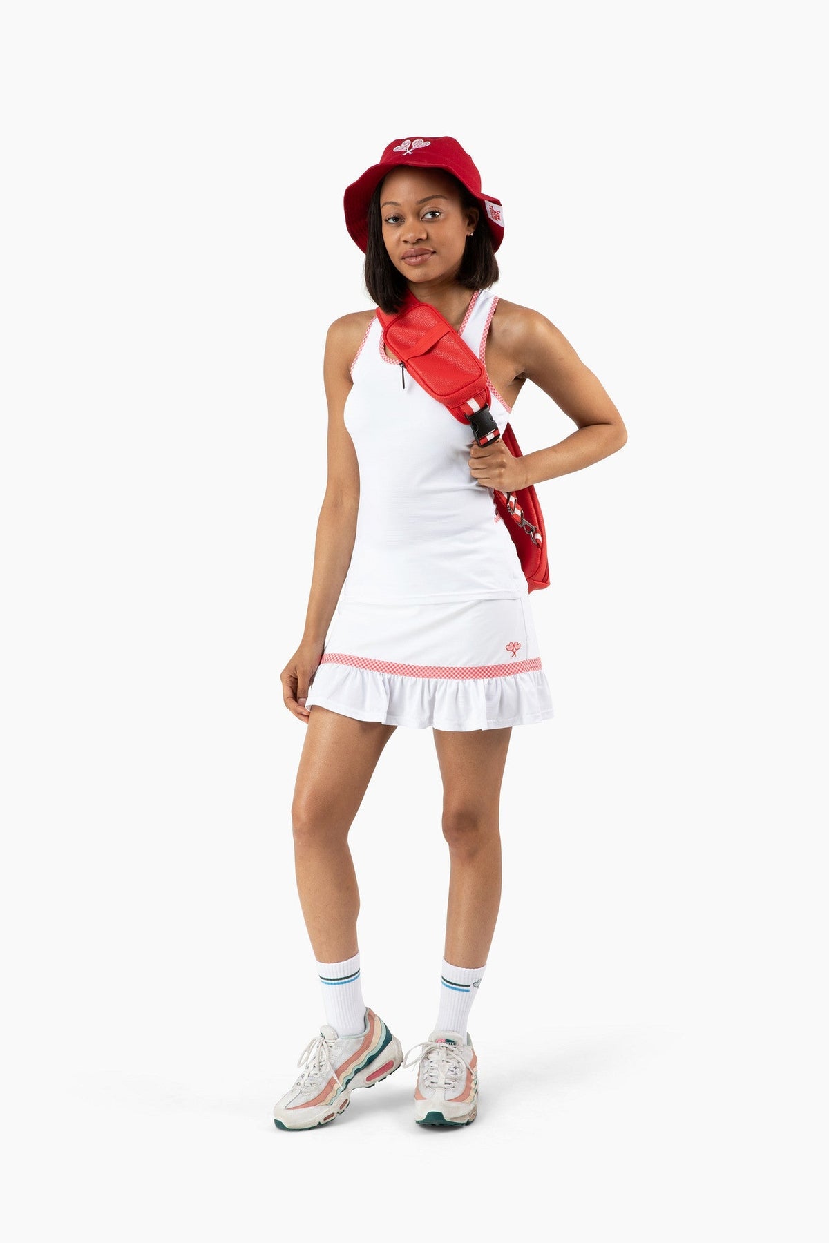 Person wearing a white tennis outfit with red accents on a white background