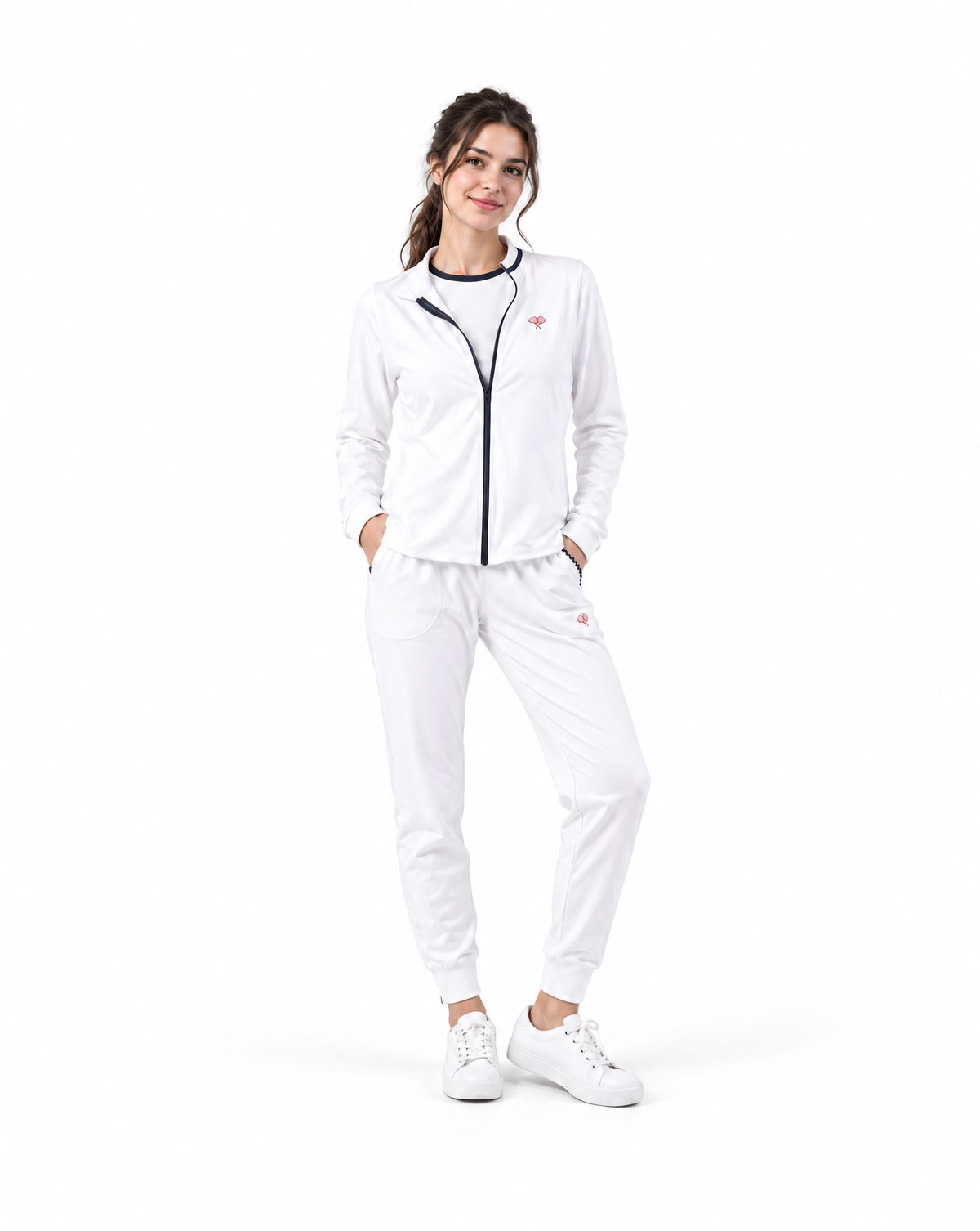A woman modeling a white athletic tracksuit with a zip-up jacket and matching jogger pants, featuring a small red logo on the chest, set against a plain white background.