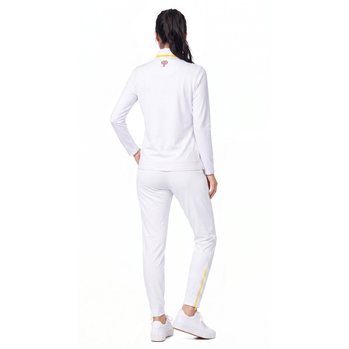 A woman shown from the back wearing a white athletic tracksuit with a long-sleeve top and matching jogger pants, featuring small yellow and red accents on the collar and leg.