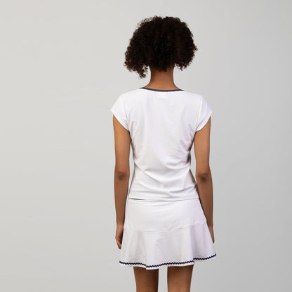 Person wearing a white tennis skort and top with a skirt on a plain background