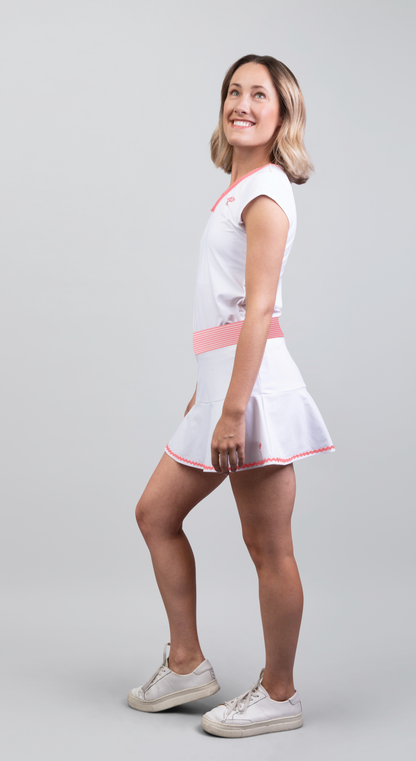 Woman wearing a white dress with pink accents on a gray background