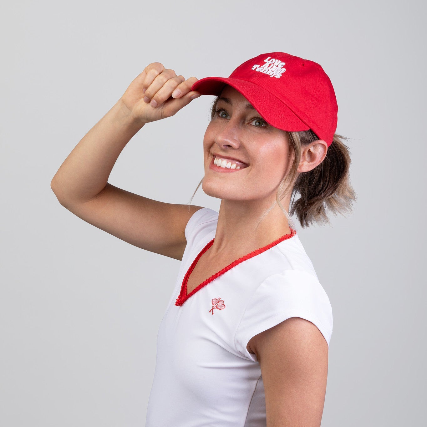 Woman wearing a red and white outfit with a matching cap on a gray background